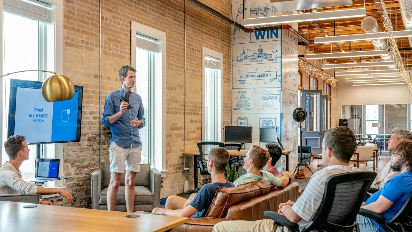 A teammate presenting to the company in a brick-walled office