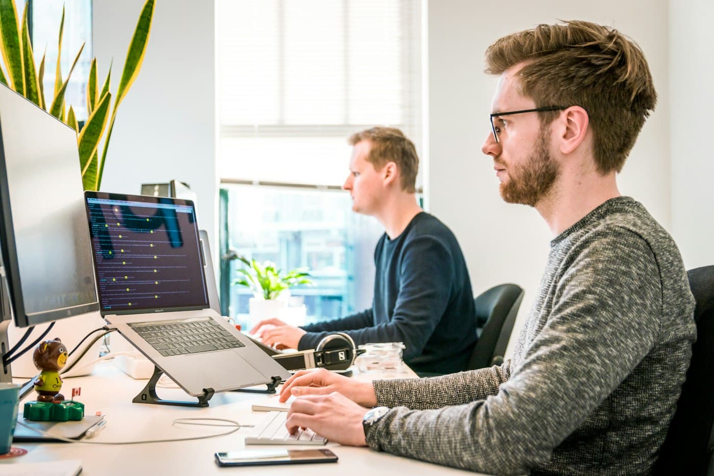 Two developers working side by side at a bright desk
