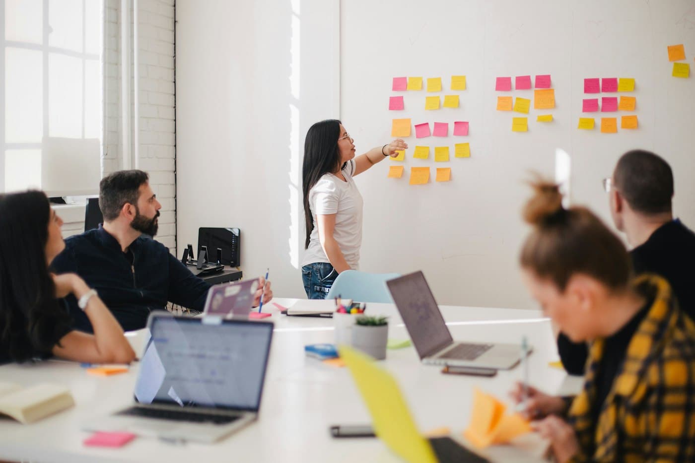 A teammate presenting sticky notes on a whiteboard to a workshop