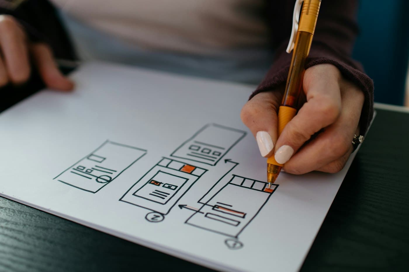 A hand sketching app wireframes on paper